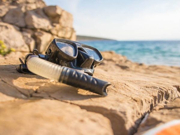 Snorkel gear resting on a rock beside the beach.