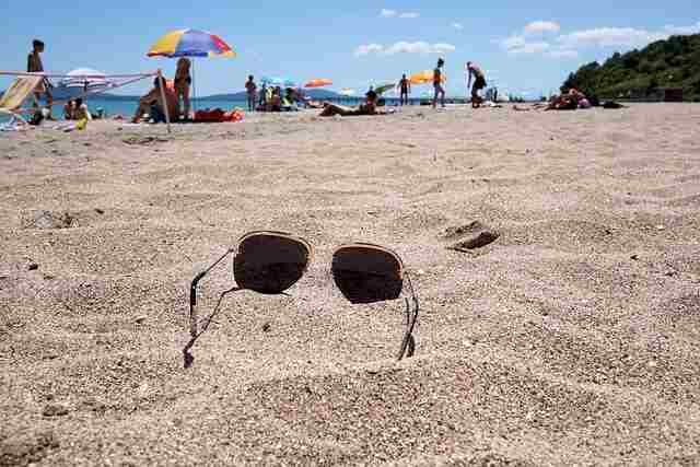 A pair of sunglasses on the beach sand.