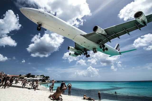A plane landing on the runway off of the dangerous Maho beach.