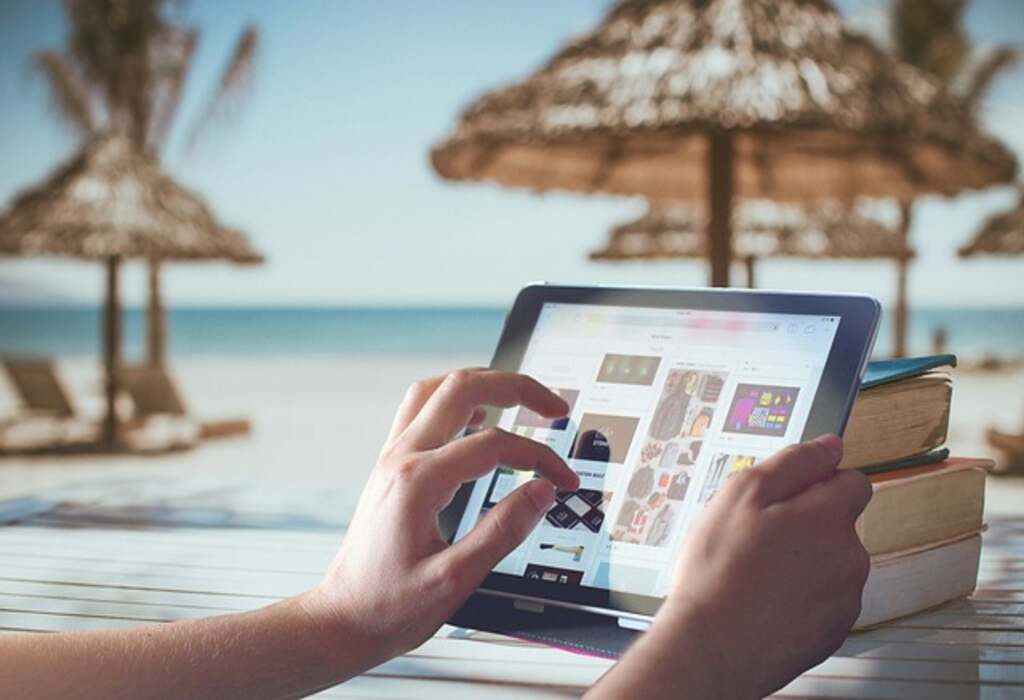 A person at the beach on a tablet.